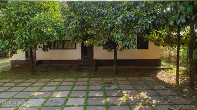 a building with two trees in front of it at The Mangosteen Homestay in Kodanad
