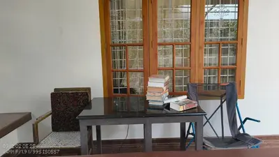 a table with books on it next to a window at The Mangosteen Homestay in Kodanad