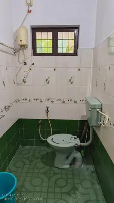 a bathroom with a green and white toilet and a window at The Mangosteen Homestay in Kodanad