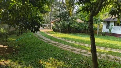a cobblestone path in a yard next to a house at The Mangosteen Homestay in Kodanad