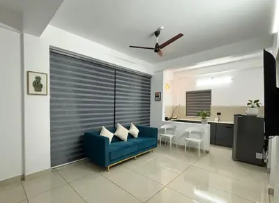 a living room with a blue couch and a kitchen at Lakshmi Home in Trichūr