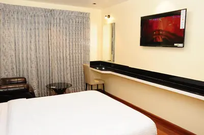 a hotel room with a bed and a tv on the wall at Vgrand in Ooty