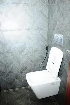 a white toilet in a bathroom with a tiled wall at Vgrand in Ooty