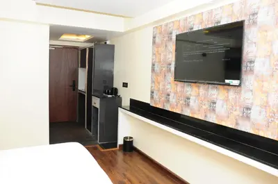 a hotel room with a large tv on a wall at Vgrand in Ooty