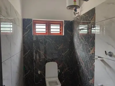 a bathroom with a toilet and a window at Empire Life Pool Villa in Meenangadi