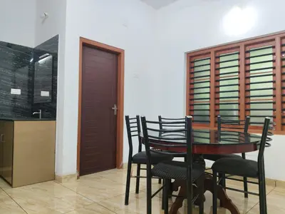 a dining room with a wooden table and chairs at Empire Life Pool Villa in Meenangadi