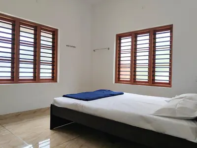 a bedroom with a bed and two windows at Empire Life Pool Villa in Meenangadi