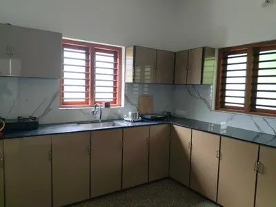 a kitchen with wooden cabinets and a sink and two windows at Empire Life Pool Villa in Meenangadi