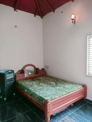 a bedroom with a bed in the corner of a room at MVR Home Stay in Seringapatam