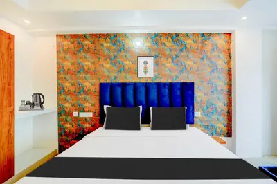 a bedroom with a large bed with a blue headboard at Collection O City Bus Station Mysuru in Mysore