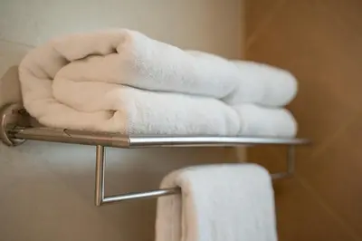 a pile of towels on a towel rack in a bathroom at Royal Plaza Glitz Inn in Kozhikode