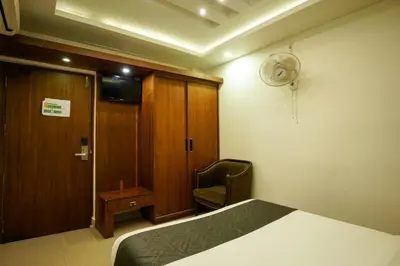 a bedroom with a bed and a chair and a door at Royal Plaza Glitz Inn in Kozhikode