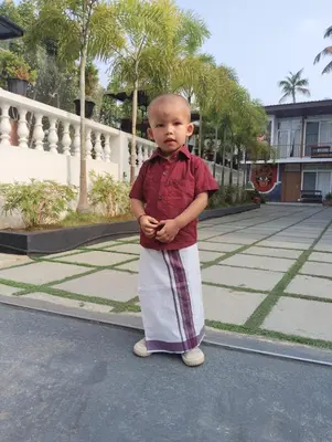 a young boy standing in the street with his hands in his pocket at Lake view Resort cherai in Cherai Beach