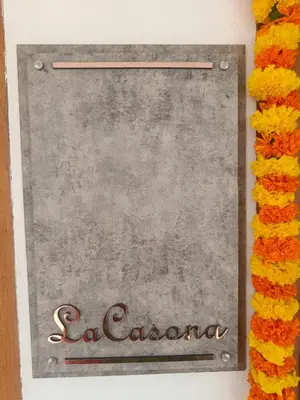 a sign for a restaurant with flowers around it at La- casona in Kottayam