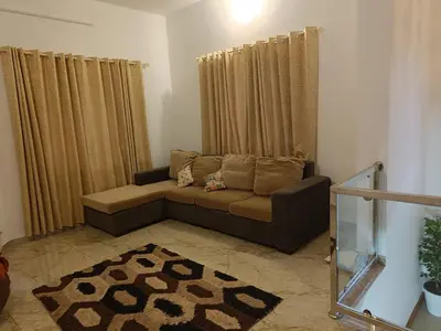 a living room with a brown couch and curtains at La- casona in Kottayam