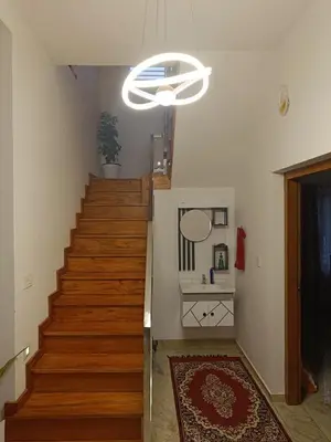 a hallway with a staircase with a white chandelier at La- casona in Kottayam