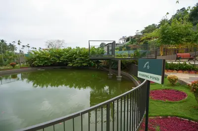 a sign in front of a pond in a park at EVORA Resort and SPA in Ambalavayal