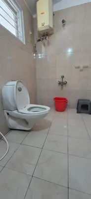a bathroom with a toilet and a red bucket at Classic Homestay Hills Ooty in Ooty