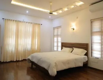 a bedroom with a large bed and two windows at Village Pavilion in Tellicherry