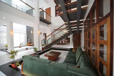 a living room with a green couch and a staircase at Village Pavilion in Tellicherry