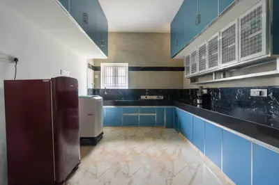 a large kitchen with blue cabinets and a refrigerator at Meenakshi residency in Alāndurai