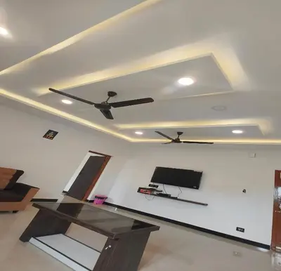 a living room with a ceiling fan and a tv at The Canalway Inn in Pollāchi