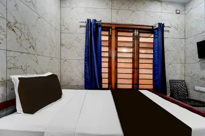 a bedroom with a bed and a window with blue curtains at Super Collection O Omni Bus Terminal Gandhipuram Formerly Apple Grand in Coimbatore