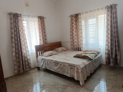 a bedroom with a bed and two large windows at La-Casona in Kottayam