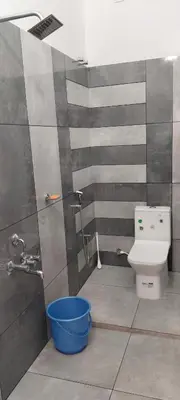 a bathroom with a toilet and a blue bucket at La-Casona in Kottayam