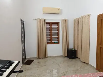 a living room with a piano and a window at La-Casona in Kottayam