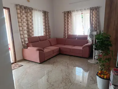 a living room with a pink couch in front of two windows at La-Casona in Kottayam