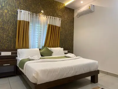 a bedroom with a bed with white sheets and a window at Wayanad Mona Villa in Wayanad