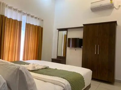 a bedroom with two beds and a cabinet and a television at Wayanad Mona Villa in Wayanad