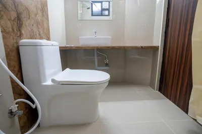 a bathroom with a white toilet and a sink at Cross Roads Inn in Coimbatore
