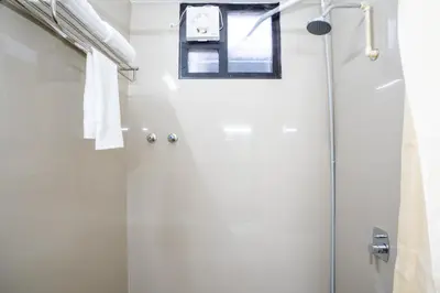 a shower with a glass door in a bathroom at Cross Roads Inn in Coimbatore