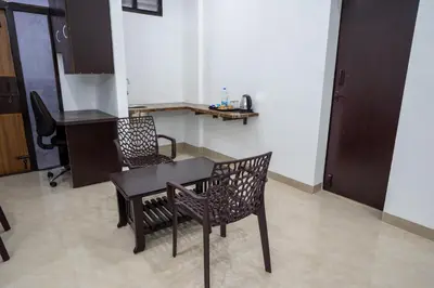 a kitchen with a table and two chairs in a room at Cross Roads Inn in Coimbatore