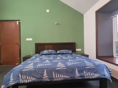 a bed with a blue comforter in a bedroom at Eden Villa in Meenangadi
