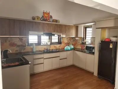 a kitchen with white cabinets and a black refrigerator at Eden Villa in Meenangadi