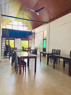 a dining room with tables and chairs and windows at Vaca Vibes Resorts in Koroth
