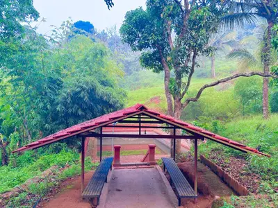 a pavilion with two red benches in a forest at Vaca Vibes Resorts in Koroth