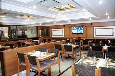 a restaurant with tables and chairs and a television at Suvarna Residency in Mysore