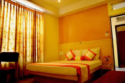 a bedroom with a bed with orange walls and orange curtains at Suvarna Residency in Mysore