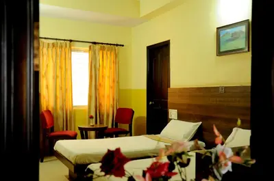 a hotel room with two beds and a table and chairs at Suvarna Residency in Mysore
