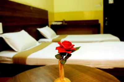 a rose in a vase on a table in a hotel room at Suvarna Residency in Mysore