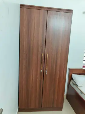 a wooden cabinet in a bedroom with a bed at Little Villa East Fort in Trichūr