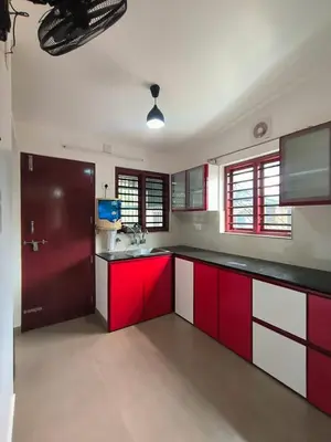 a kitchen with red and white cabinets and windows at Little Villa East Fort in Trichūr