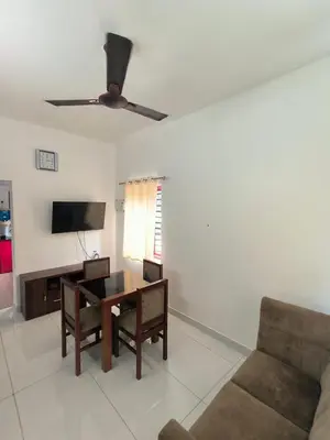 a living room with a table and a ceiling fan at Little Villa East Fort in Trichūr