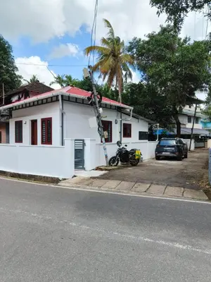 a white house with a motorcycle parked in front of it at Little Villa East Fort in Trichūr