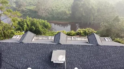a roof of a building with a lake in the background at White Fort Holiday Home in Vythiri