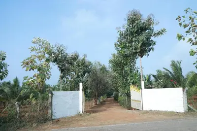 a white fence with a tree over a dirt road at Maitree Serenity Farm Stay